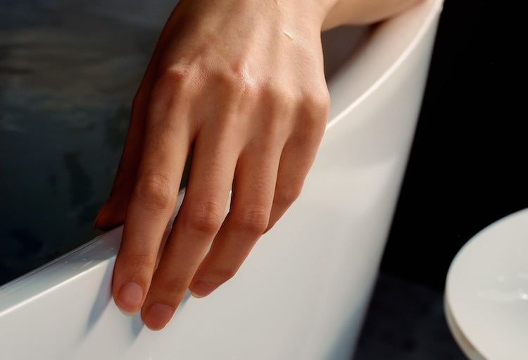 A hand resting on the edge of a BainUltra bath.